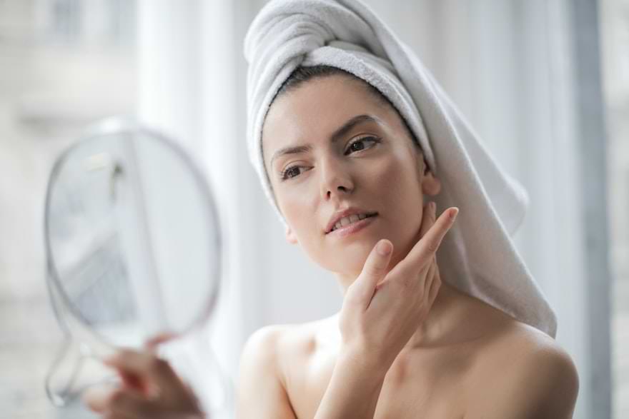 ragazza si guarda allo specchio durante la sua routine di skincare