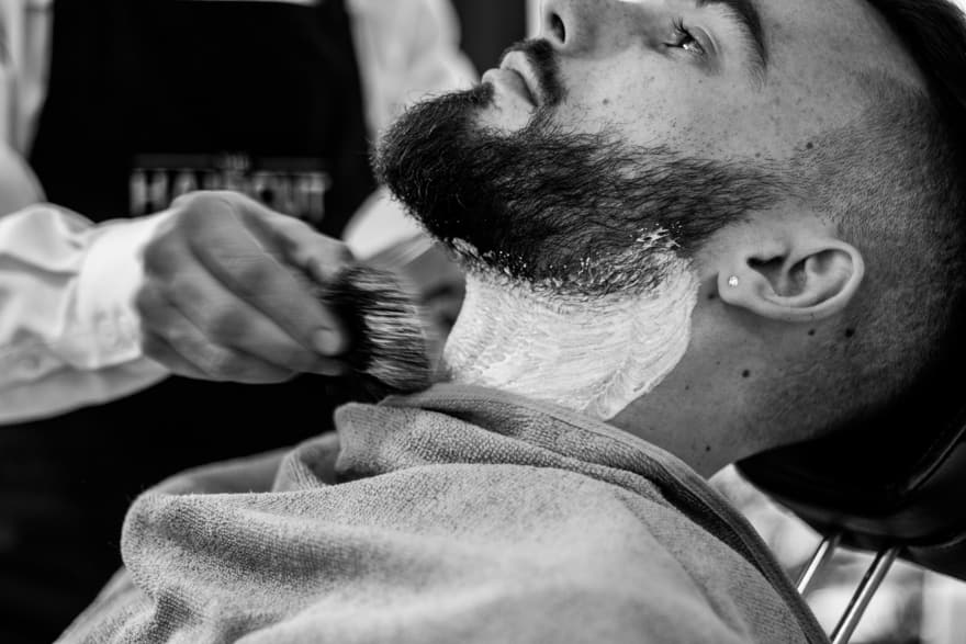 Uomo che fa la barba dal barbiere con la lama e il sapone